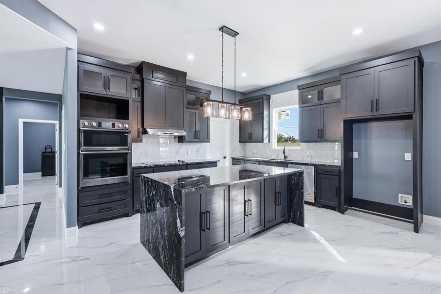 Kitchen featuring light marble finish flooring, a center island, decorative light fixtures, backsplash, and recessed lighting