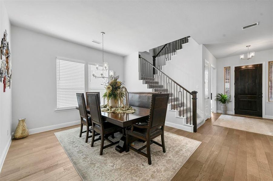 Dining space with light hardwood / wood-style floors and a notable chandelier