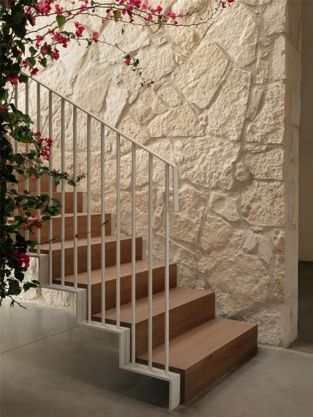 Absolute stunning foyer with limestone wall, floating staircase and views looking out over the pool.