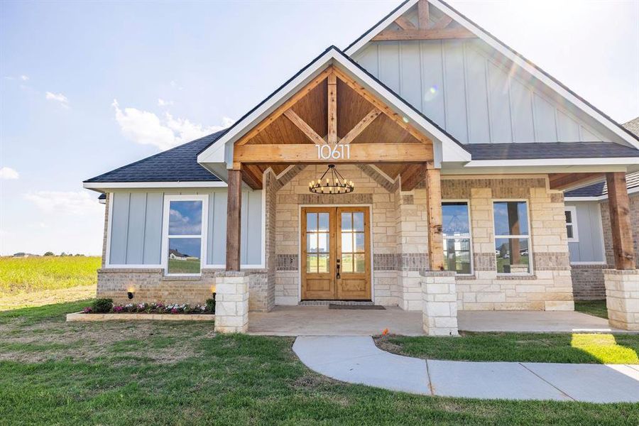 Craftsman house with board and batten siding, a shingled roof, french doors, stone siding, and a front yard Craftsman house with board and batten siding, a shingled roof, french doors, stone siding, and a front yard