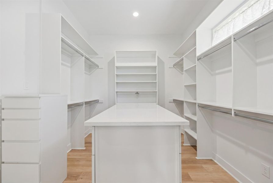 Ample built-in shelving and storage island organize a wardrobe with ease.