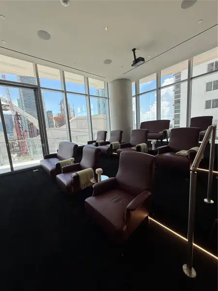 Floor-to-ceiling windows, tiered seating platform with integrated stair lighting, ceiling-mounted projection system, and recessed overhead lighting