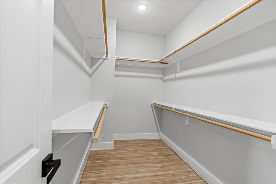 Spacious walk-in closet with custom shelving, double hanging rods, and built-in storage.Well-lit design offers ample organization for wardrobe and accessories.