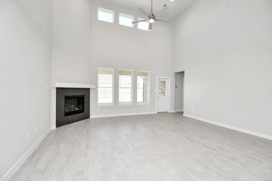 Family room flooded with natural light through the expansive windows.  The premium tile flooring adds a touch of luxury to the space, creating the perfect setting for relaxing moments and cherished gatherings with loved ones. Sample photo of completed home with similar floor plan. Actual colors and selections may vary.