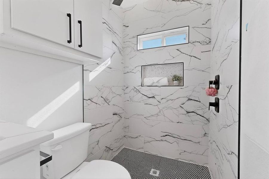 Full bath featuring a marble finish shower and vanity