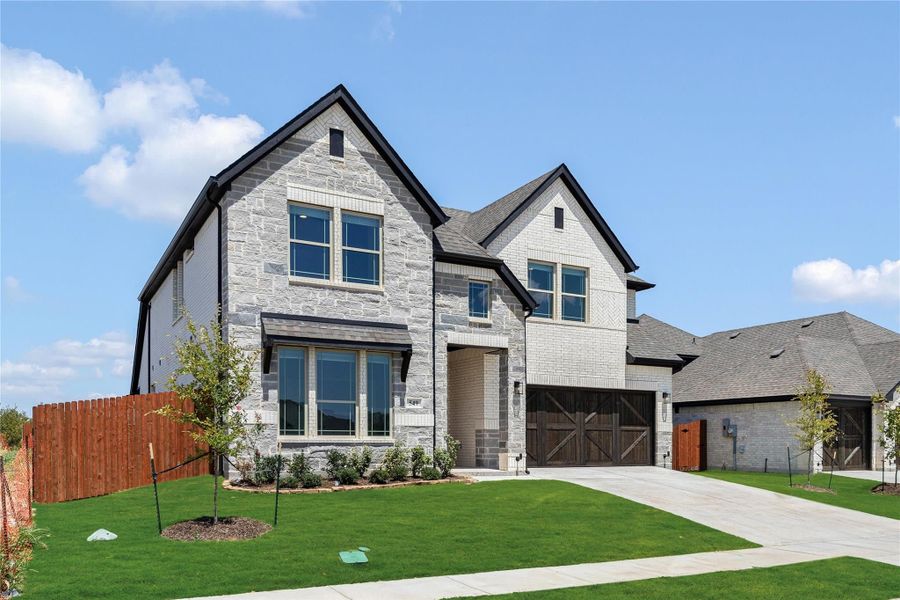 Two-story home with light stone exterior, dark wood garage door, and manicured front lawn