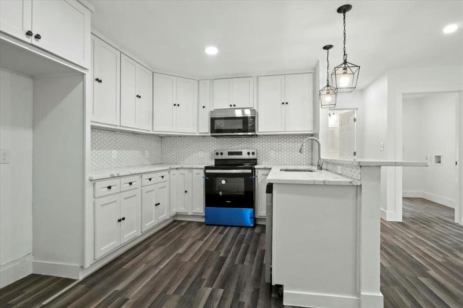 Kitchen with appliances with stainless steel finishes, white cabinetry, and sink