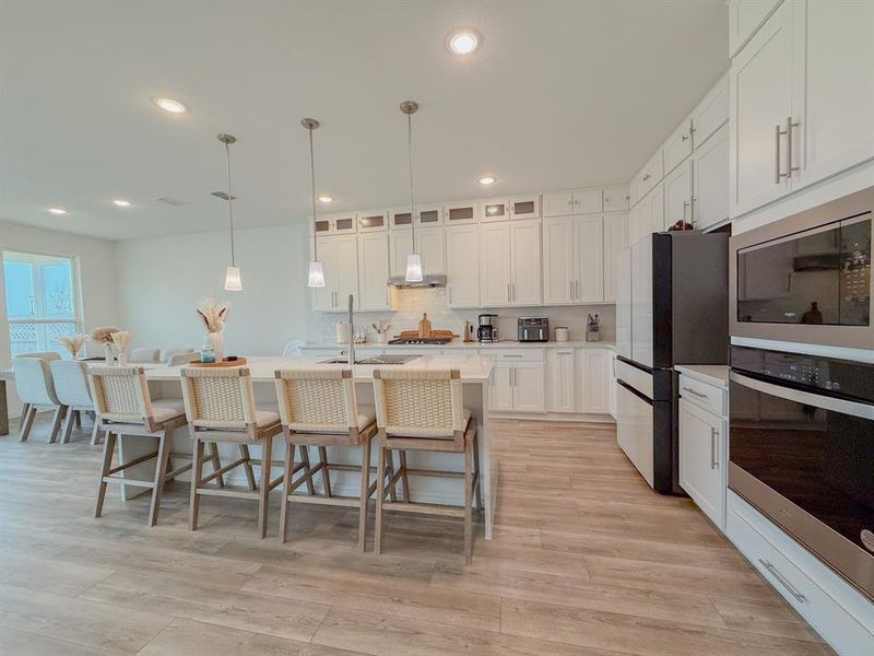 Kitchen featuring a breakfast bar area, stainless steel appliances, light wood-style floors, light countertops, and backsplash