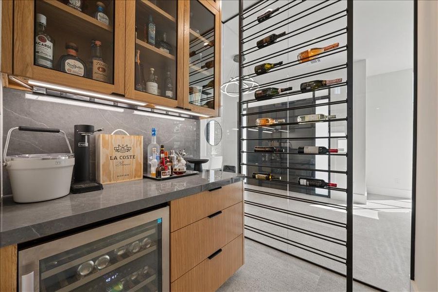 Wine area featuring beverage cooler, dark aggregate flooring, and a dry bar