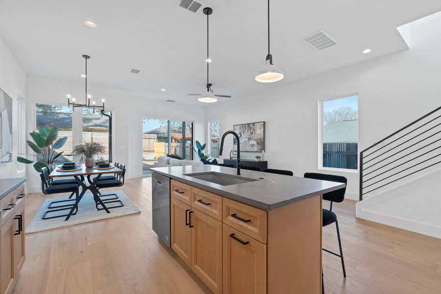 Kitchen with stainless steel dishwasher, light wood-style floors, visible vents, and a sink