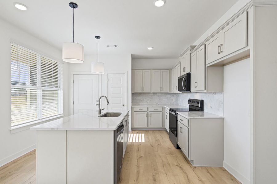 Kitchen with stainless steel appliances, light stone counters, pendant lighting, decorative backsplash, and recessed lighting