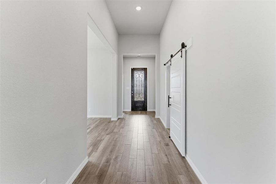 Doorway with a barn door, wood finished floors, and recessed lighting