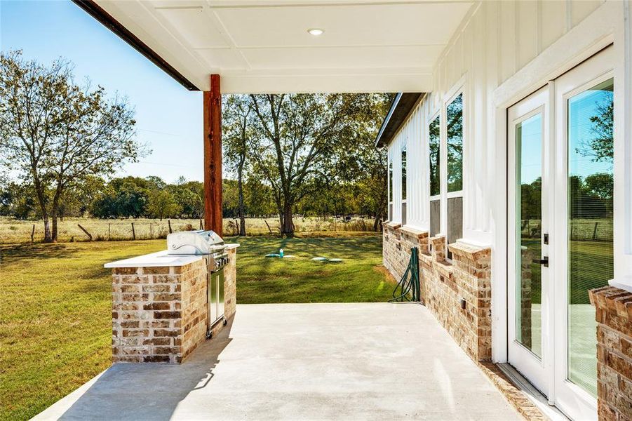 Fenced backyard with area for grilling and a patio