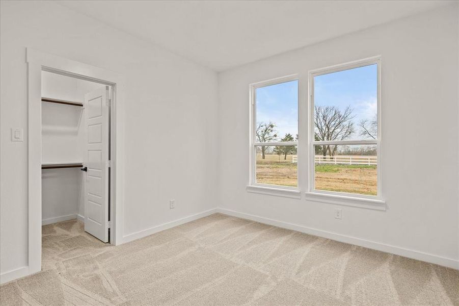 Unfurnished bedroom featuring a closet, a spacious closet, and light carpet