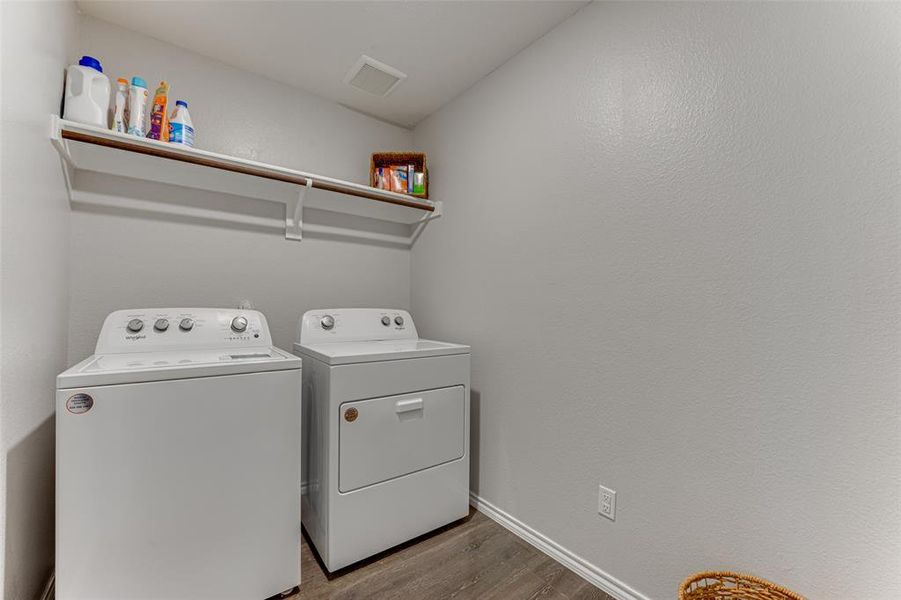 Clothes washing area with washer and clothes dryer and wood-type flooring