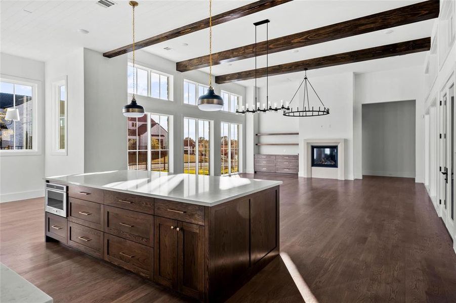Kitchen with dark brown cabinets, pendant lighting, dark wood-style floors, open floor plan, and a towering ceiling Kitchen with dark brown cabinets, pendant lighting, dark wood-style floors, open floor plan, and a towering ceiling