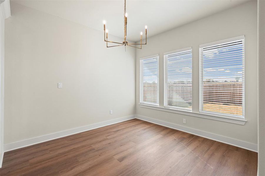 Empty room featuring wood finished floors and a chandelier