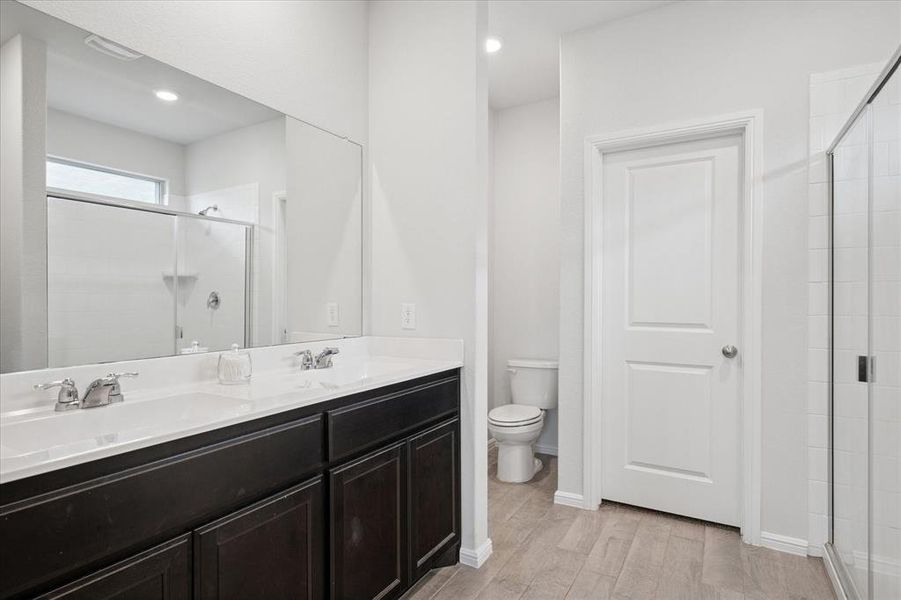 Bathroom with a shower, light wood-style flooring, double vanity, and recessed lighting. Bathroom with a shower, light wood-style flooring, double vanity, and recessed lighting.