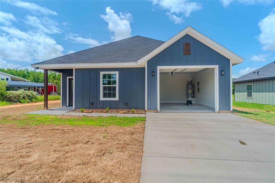 View of front of house with electric water heater and a front lawn