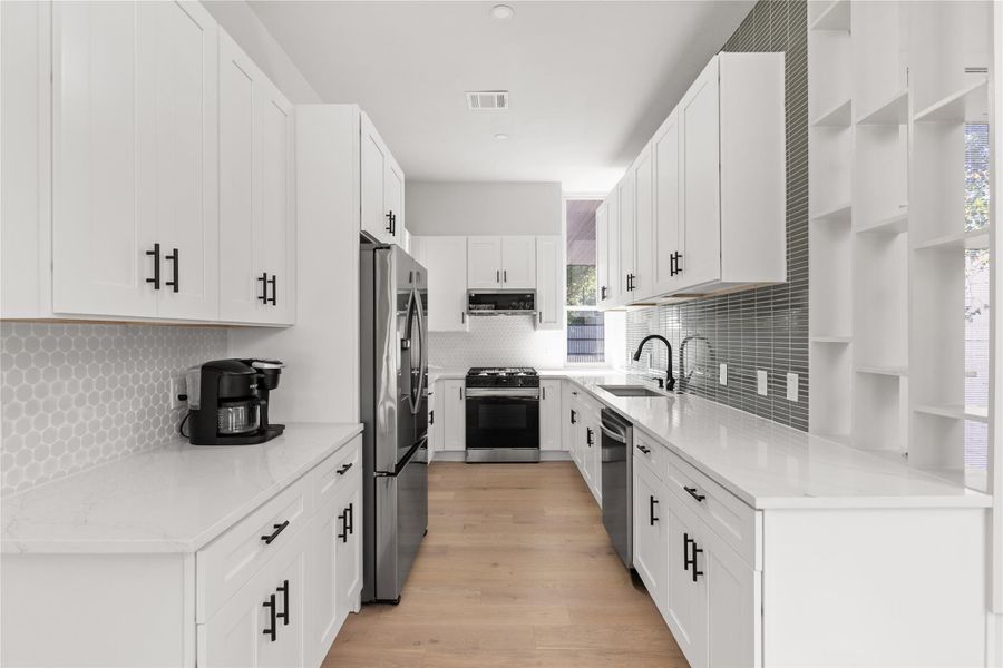 Kitchen with open shelves, light stone counters, white cabinetry, and appliances with stainless steel finishes