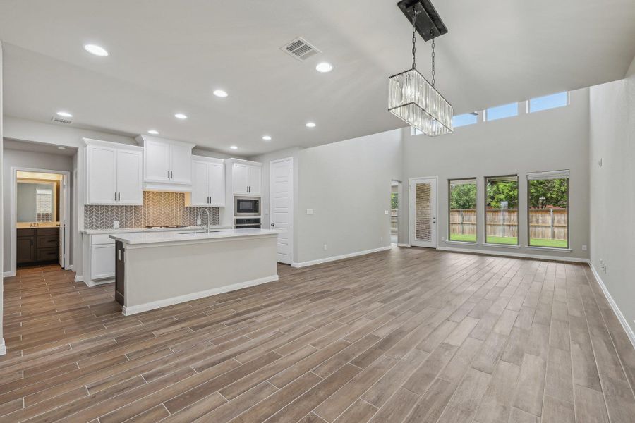 Kitchen with built in microwave, open floor plan, light countertops, an island with sink, and decorative backsplash Kitchen with built in microwave, open floor plan, light countertops, an island with sink, and decorative backsplash