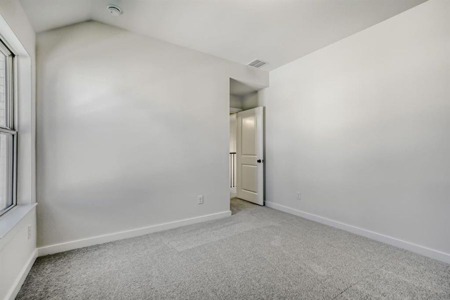 Spare room with light carpet, healthy amount of natural light, and lofted ceiling