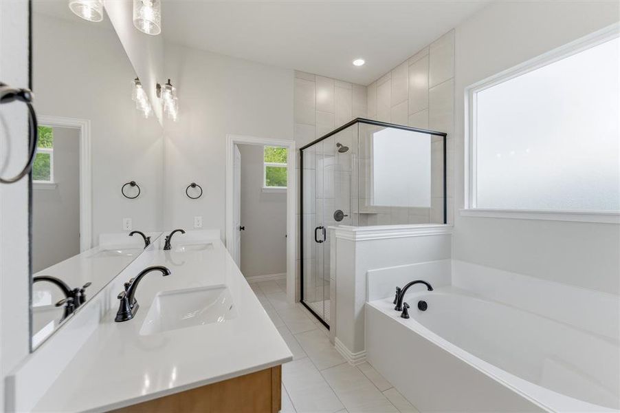 Full bath with double vanity, a stall shower, a bath, light tile patterned floors, and recessed lighting