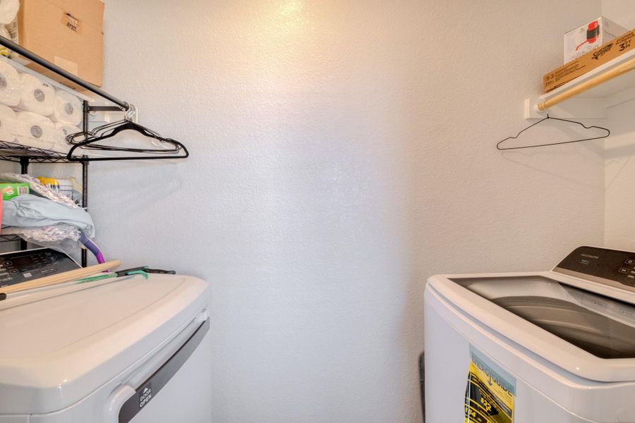 Dedicated laundry area featuring a washer and a dryer, with shelving for additional storage