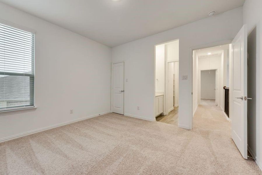 Unfurnished bedroom with connected bathroom, a closet, a spacious closet, and light colored carpet