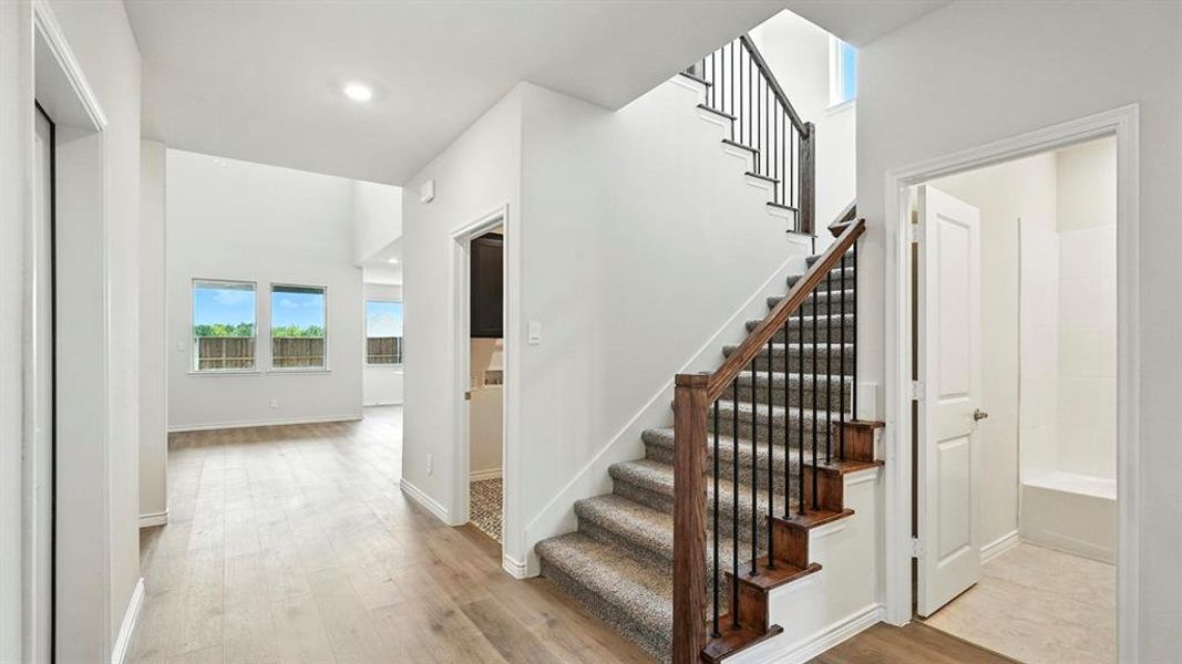 Foyer featuring a grand staircase with dark wood newel posts, banister, and wrought iron balusters