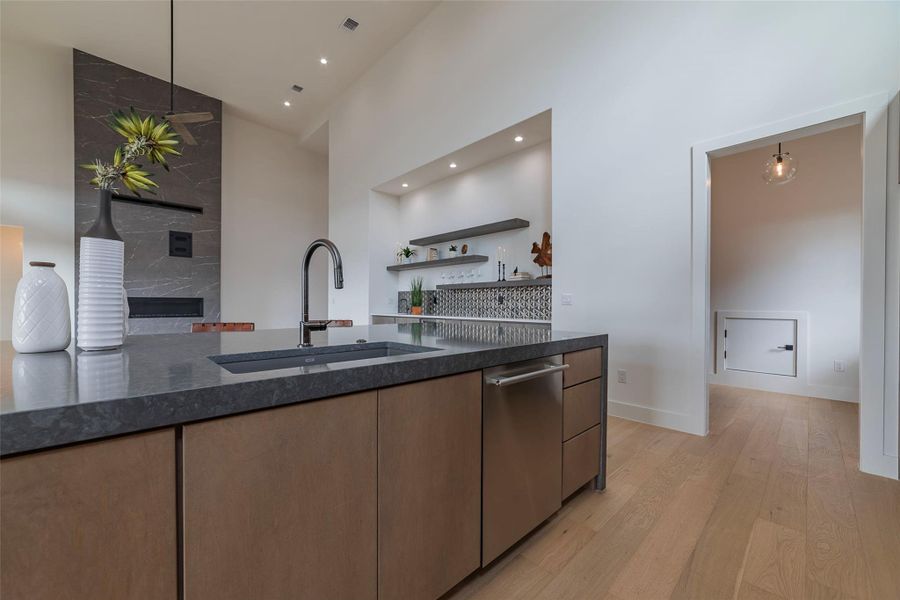 Kitchen featuring dark stone countertops, modern cabinets, open shelves, light wood-style floors, and a high ceiling