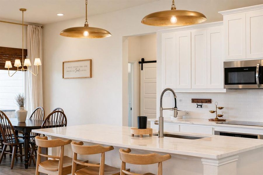 Kitchen with white paneled cabinetry, stainless steel appliances, and a white subway tile backsplash