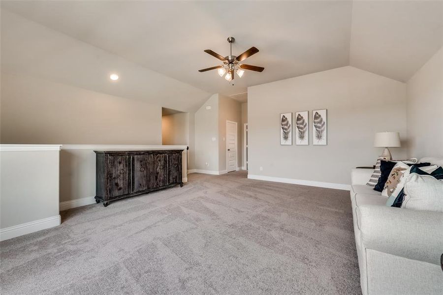 HUGE Bonus room featuring built-in shelves, vaulted ceiling, and ceiling fan