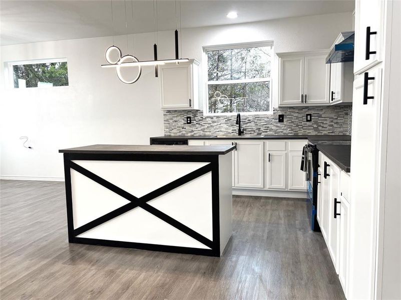 Kitchen with pendant lighting, sink, white cabinets, and range with electric cooktop