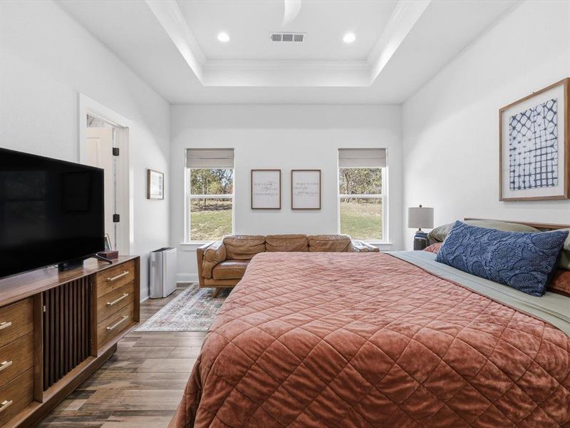 Bedroom featuring wood finished floors, crown molding, a tray ceiling, and recessed lighting