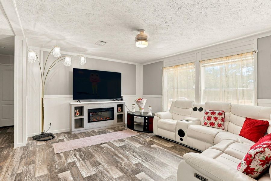 Natural light from large windows illuminates the spacious living area featuring durable wood-look flooring.
