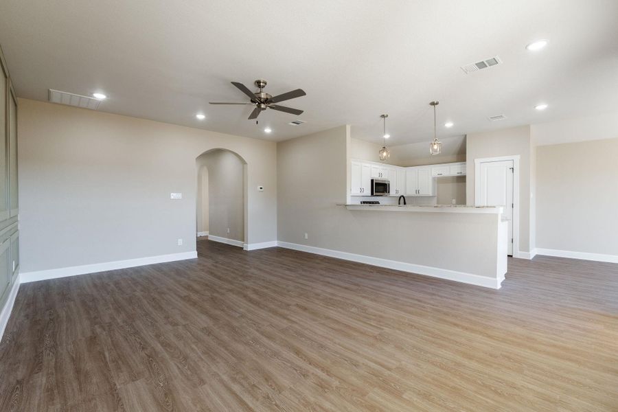 Unfurnished living room featuring arched walkways, light wood-style floors, ceiling fan, and recessed lighting