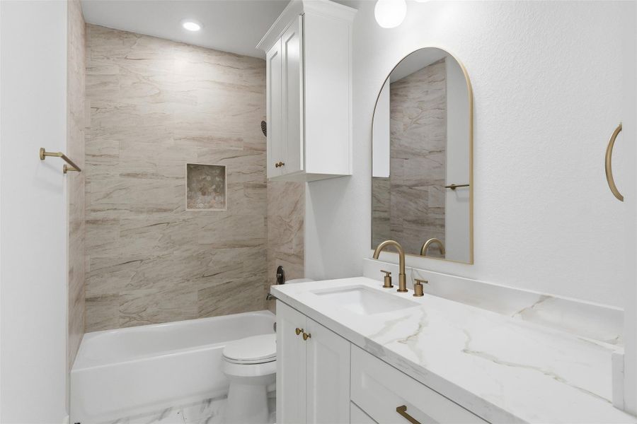 The secondary full bath features a shower-tub combo, quartz countertops, and custom cabinetry for additional storage.