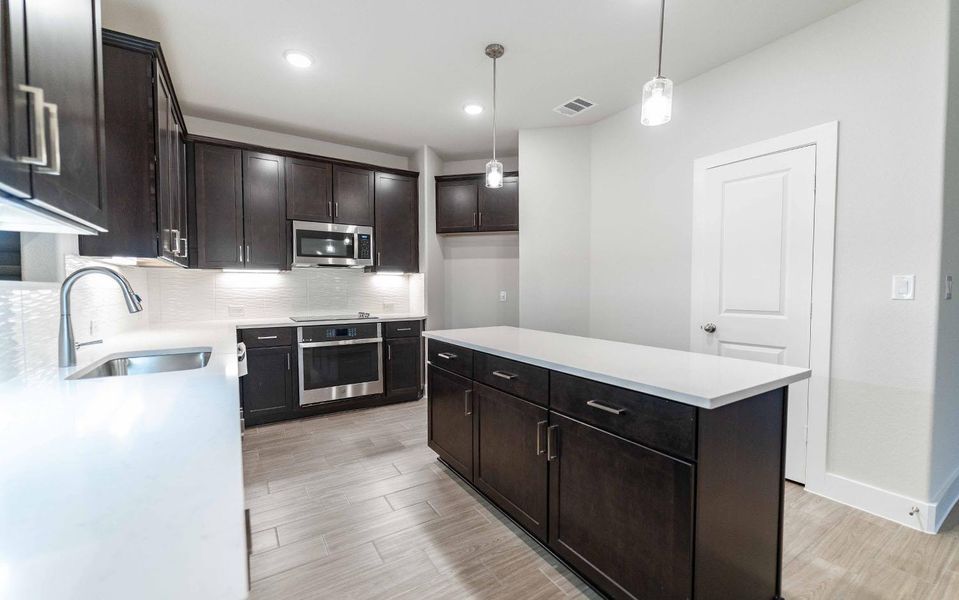 Kitchen featuring a sink, visible vents, appliances with stainless steel finishes, decorative backsplash, and pendant lighting