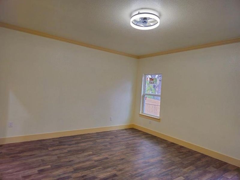 Spare room with dark hardwood / wood-style flooring, ornamental molding, and a textured ceiling