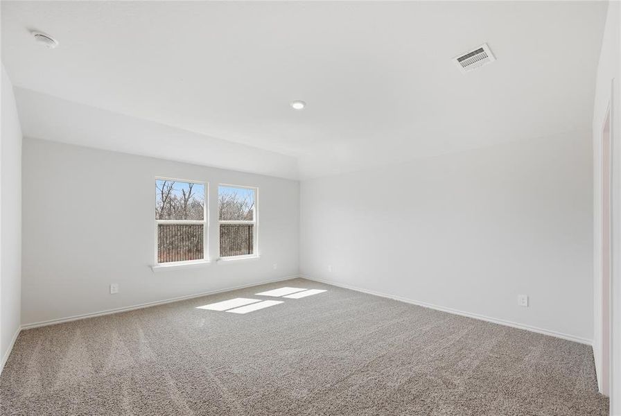 Spacious room featuring neutral carpeting, light-colored walls, and two large windows offering views of exterior trees Spacious room featuring neutral carpeting, light-colored walls, and two large windows offering views of exterior trees