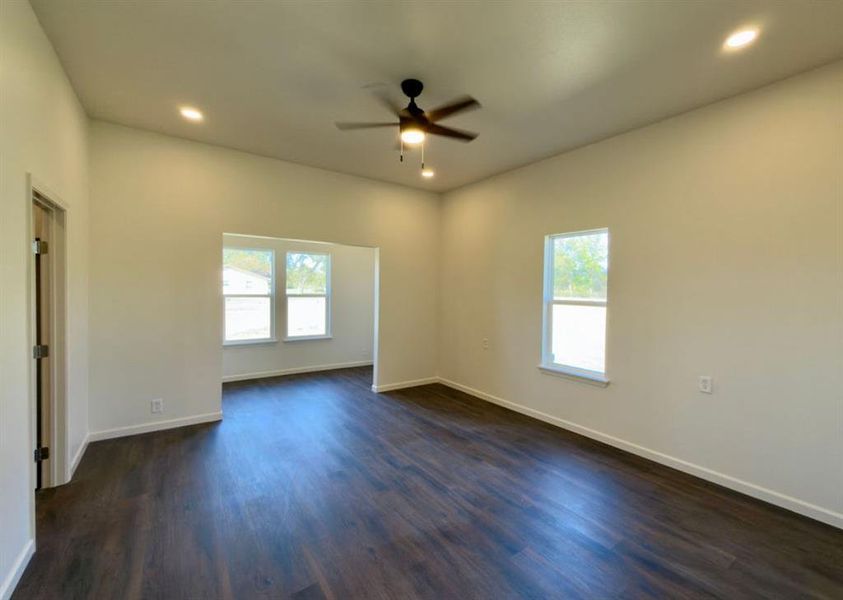 Unfurnished room with dark wood-style flooring, healthy amount of natural light, recessed lighting, and a ceiling fan Unfurnished room with dark wood-style flooring, healthy amount of natural light, recessed lighting, and a ceiling fan