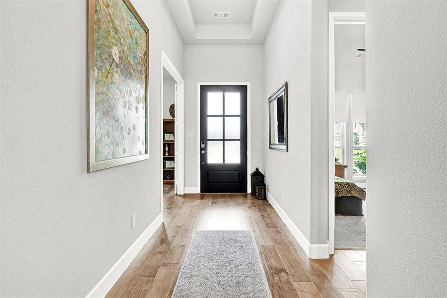 Foyer entrance featuring light wood-type flooring and a textured wall Foyer entrance featuring light wood-type flooring and a textured wall