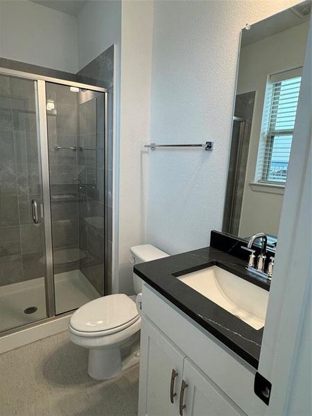 Full bath featuring vanity, toilet, and a shower stall