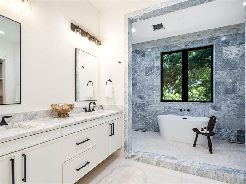 Bathroom featuring double vanity, tile walls, light tile patterned floors, a soaking tub, and recessed lighting