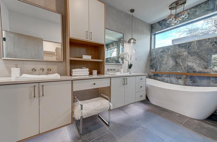 Bathroom with a sink, a soaking tub, double vanity, and tile walls