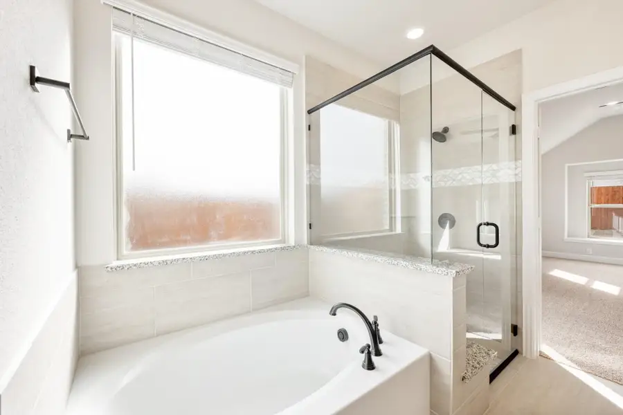 Master bathroom with soaking tub, glass-enclosed shower, and large window with white tile surround Master bathroom with soaking tub, glass-enclosed shower, and large window with white tile surround