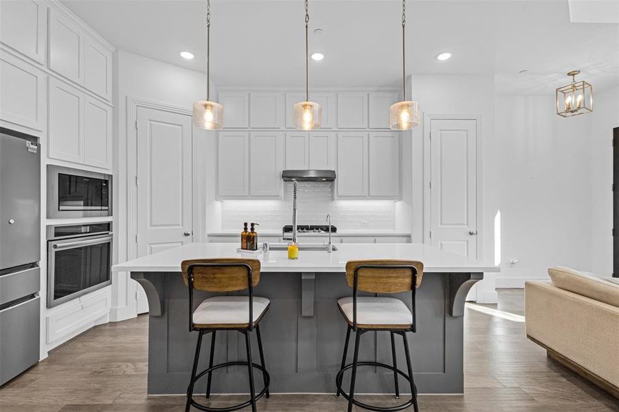 Kitchen with decorative light fixtures, a breakfast bar, stainless steel appliances, and recessed lighting