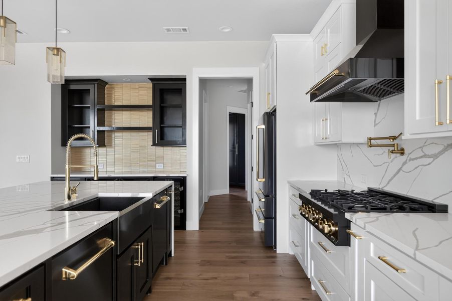Rich hardwood floors anchor this modern culinary space featuring premium stone counters and custom cabinetry.