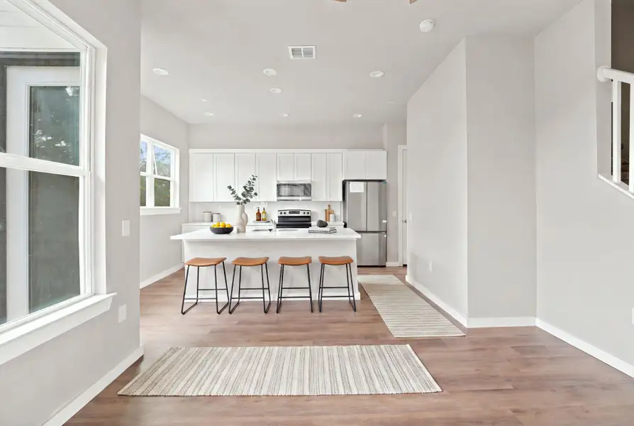 Rich wood flooring anchors this open kitchen layout framed by classic white cabinetry.